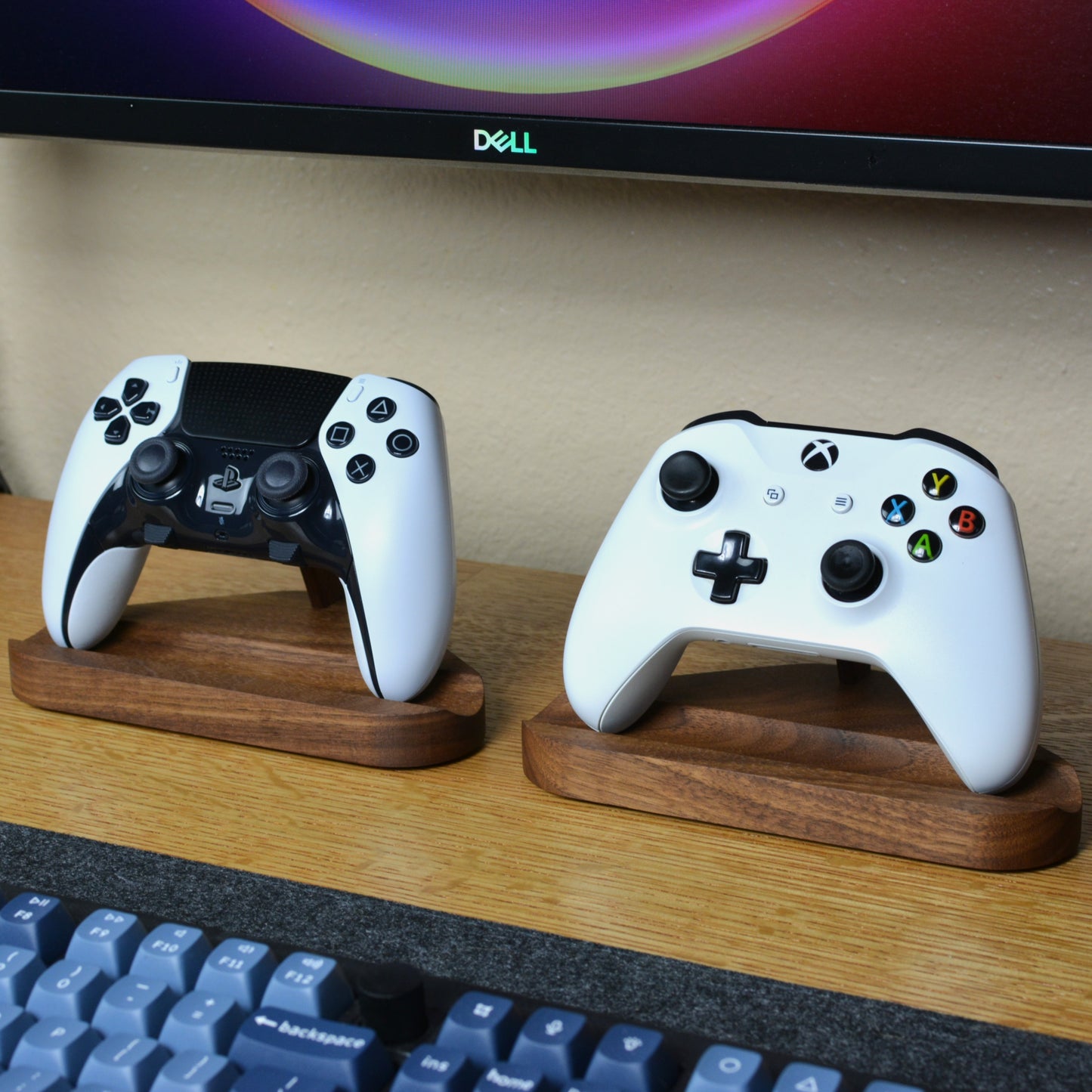 Two gaming controllers on wooden stands in front of a Dell monitor.