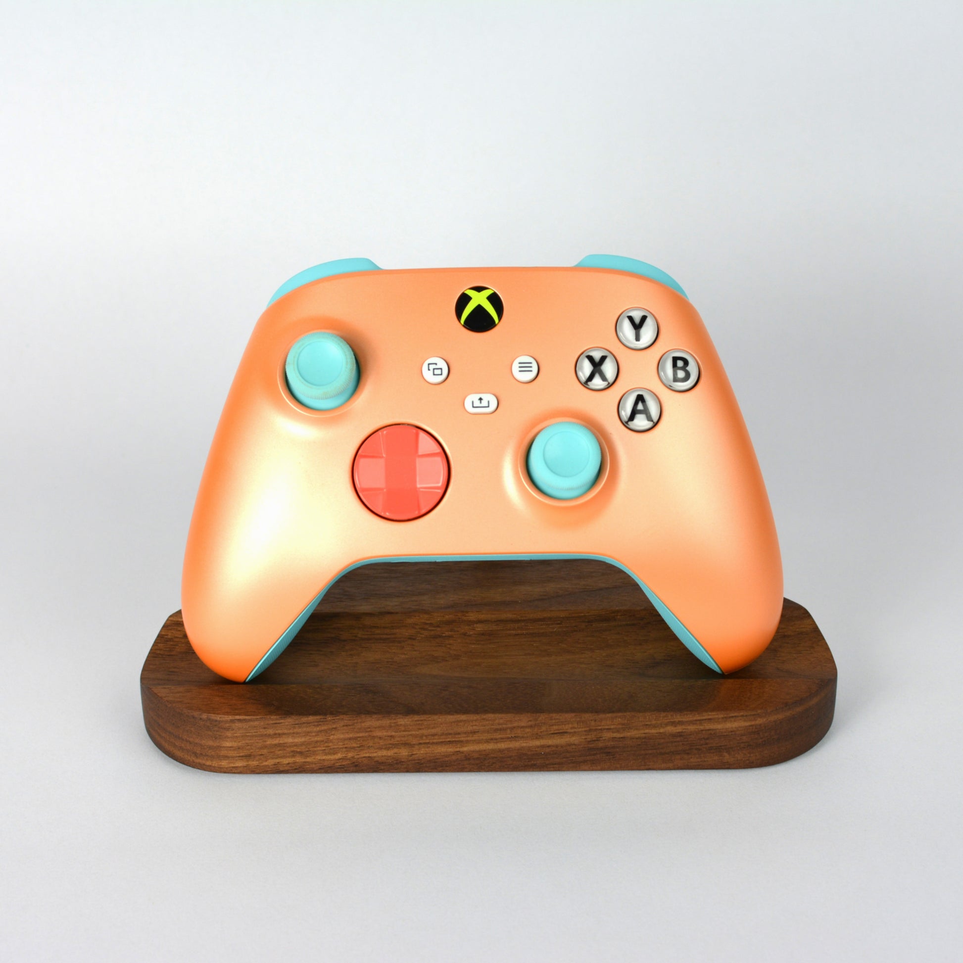 Orange gaming controller on a wooden stand with a gray background