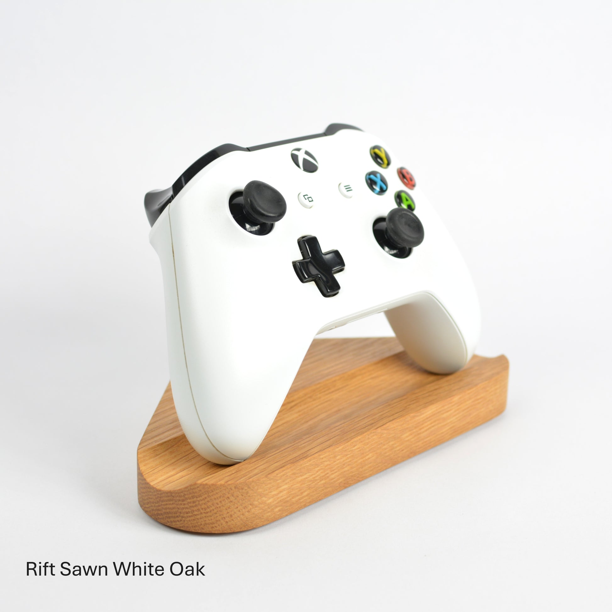 White gaming controller on a wooden stand with 'Rift Sawn White Oak' text.