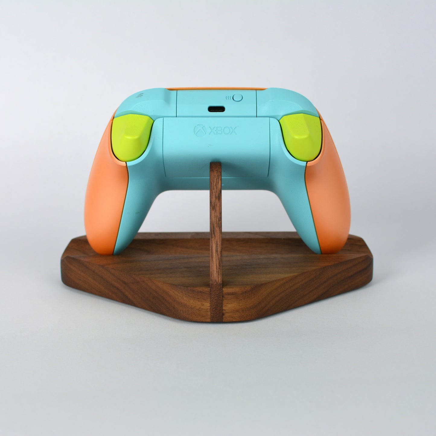 Colorful gaming controller on a wooden stand with a white background