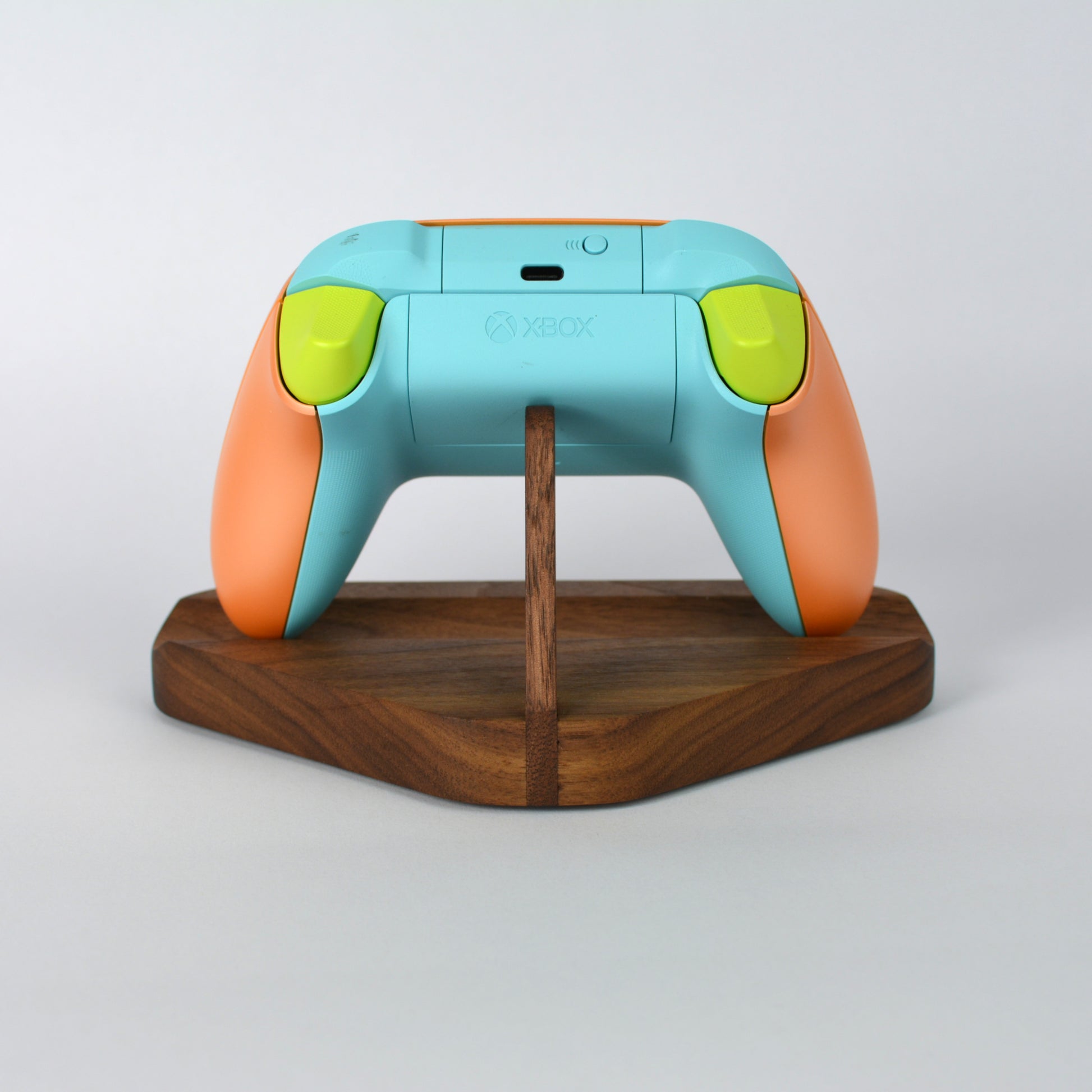 Colorful gaming controller on a wooden stand with a white background
