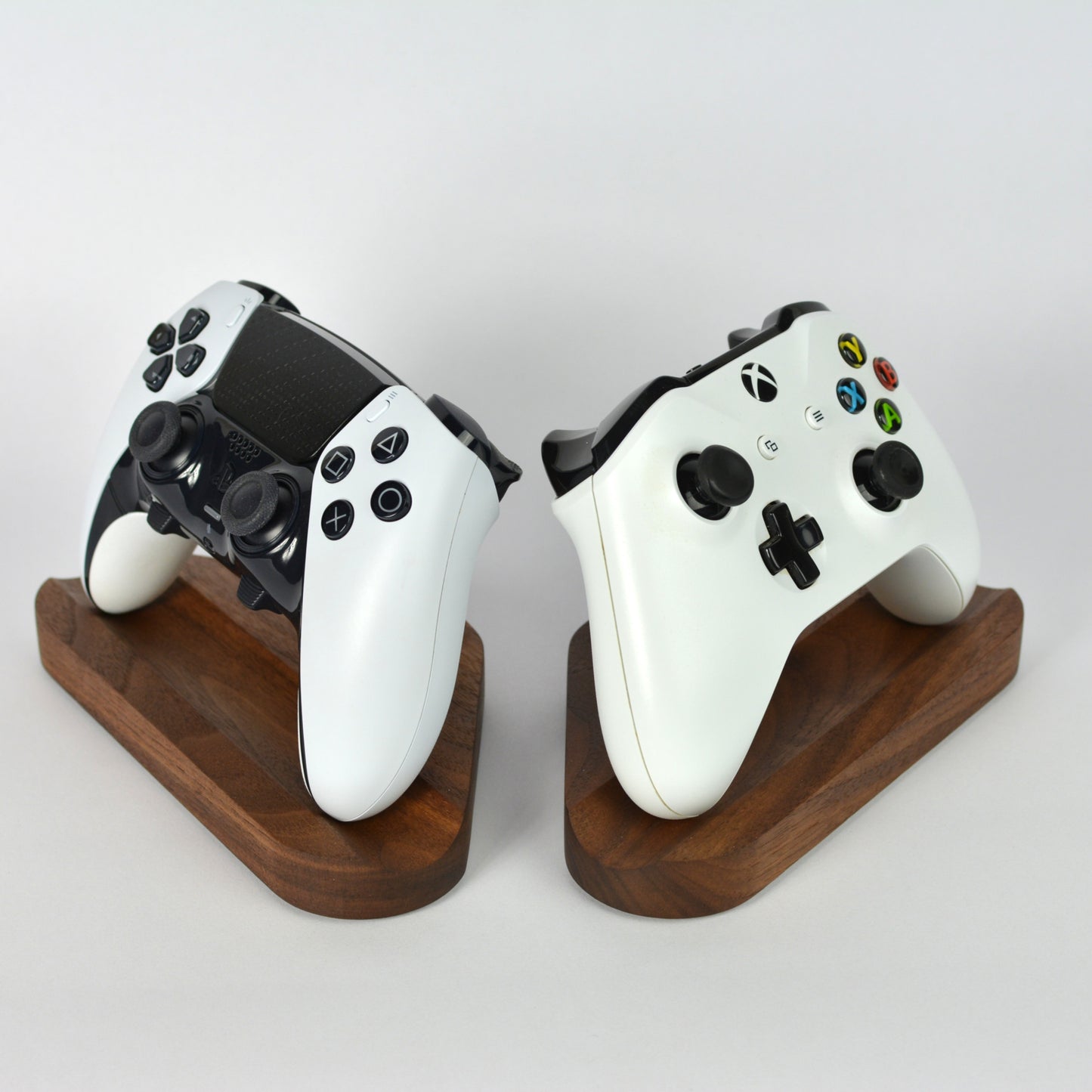 Two gaming controllers on wooden stands against a white background