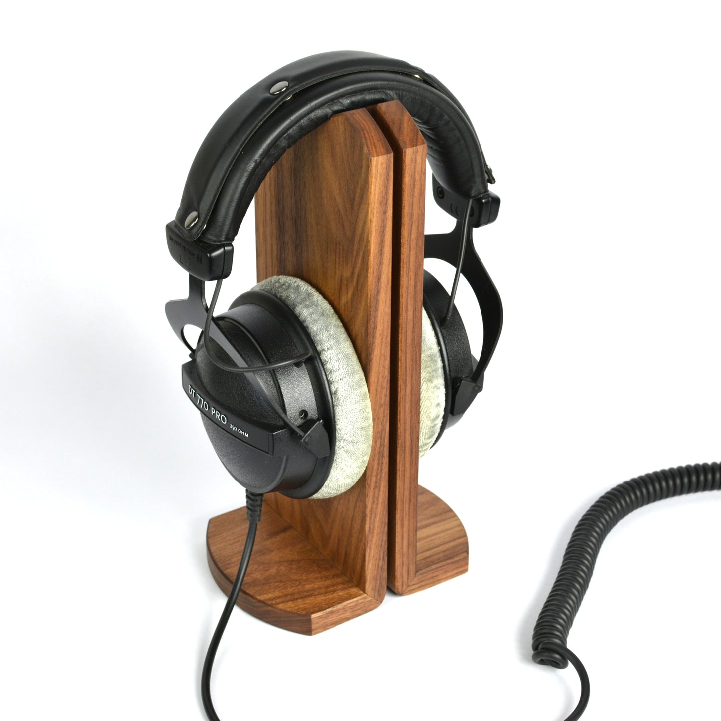 Wooden headphone stand holding a pair of headphones on a white background