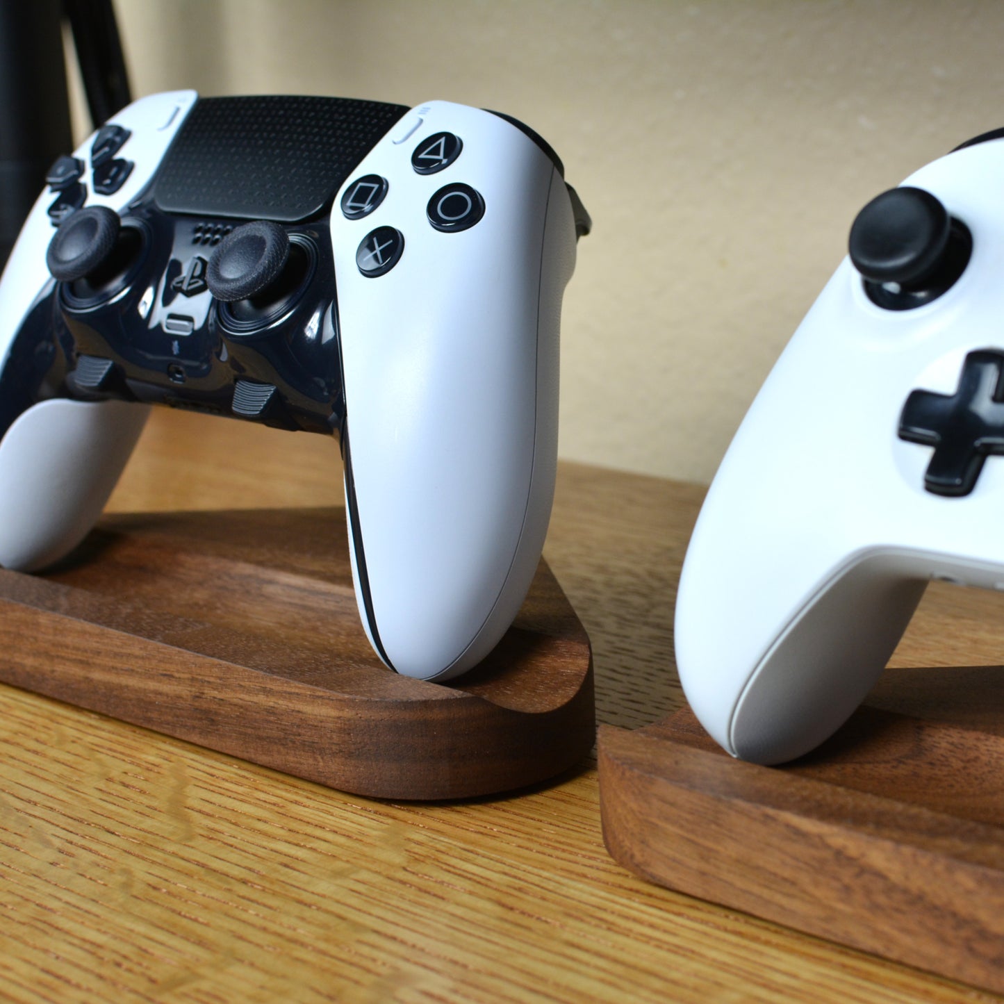 Two gaming controllers on wooden stands with a neutral background