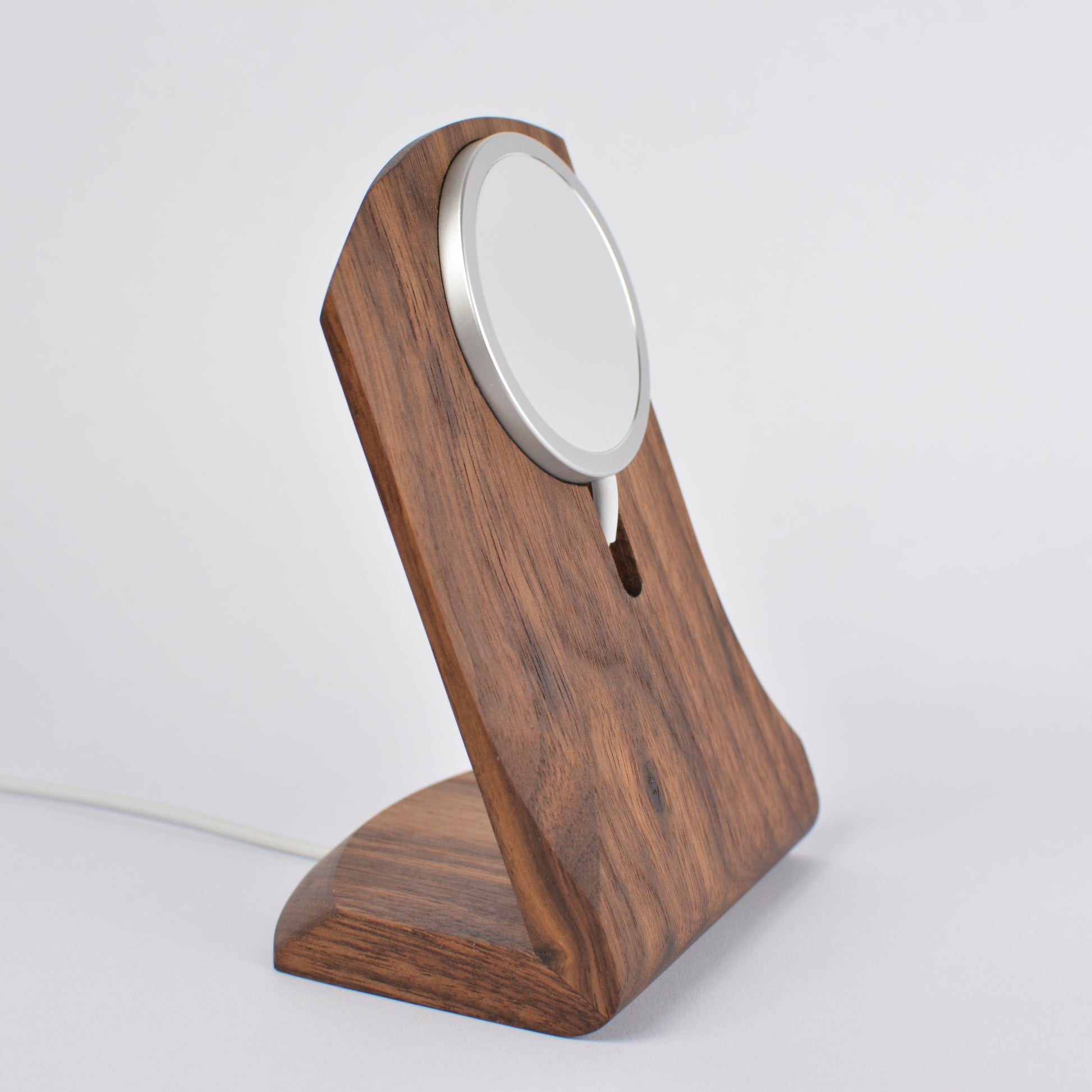 Wooden charging stand with a white circular device on a light gray background