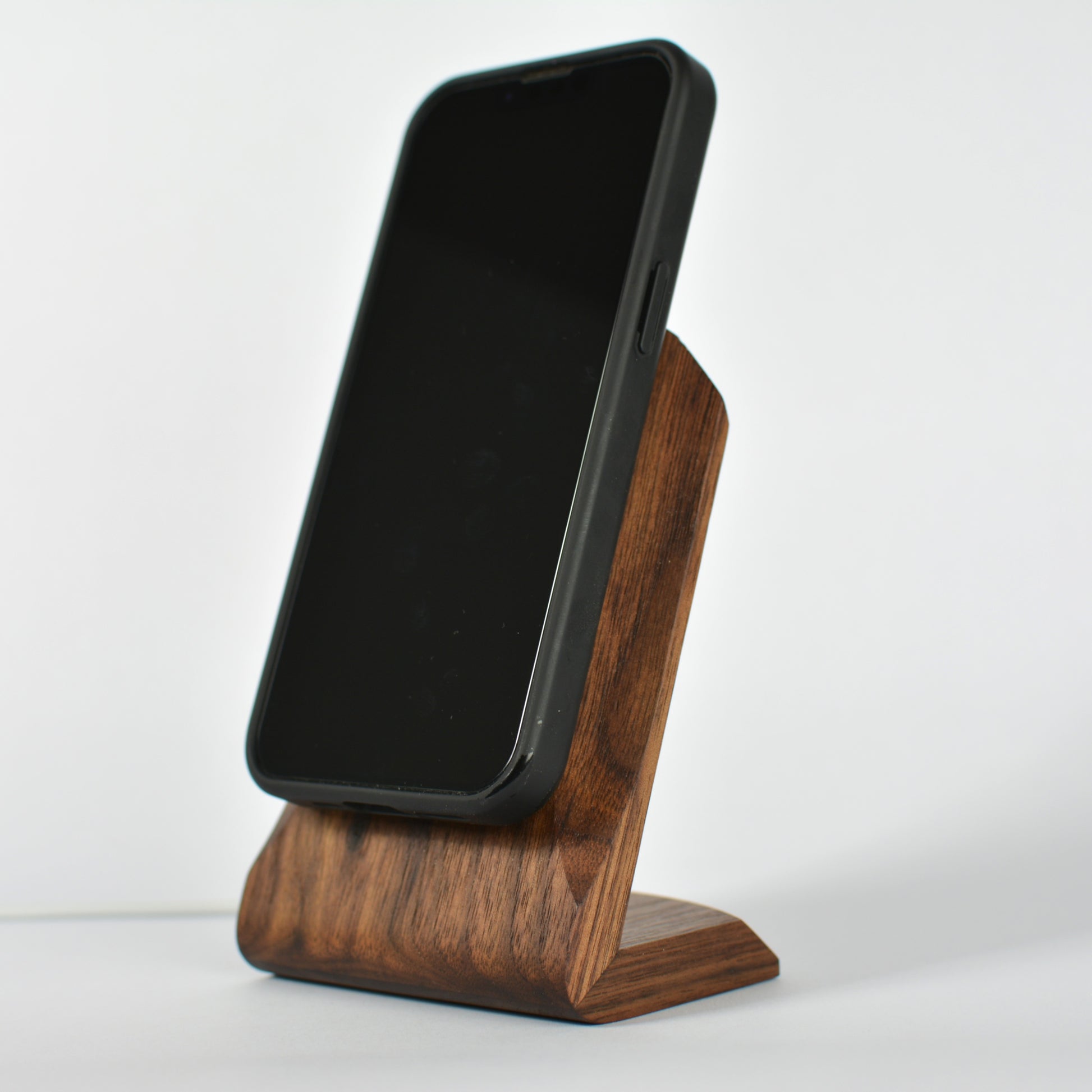 Black smartphone on a wooden stand against a white background