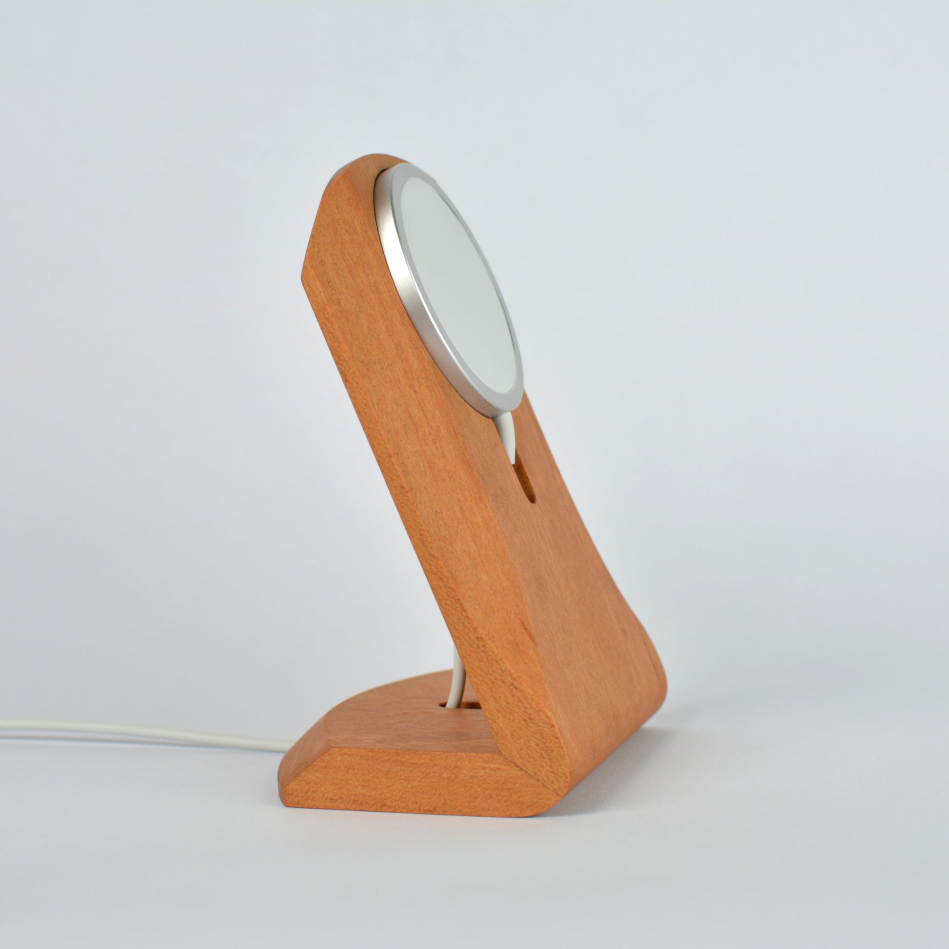 Wooden charging stand with a circular device on a light gray background