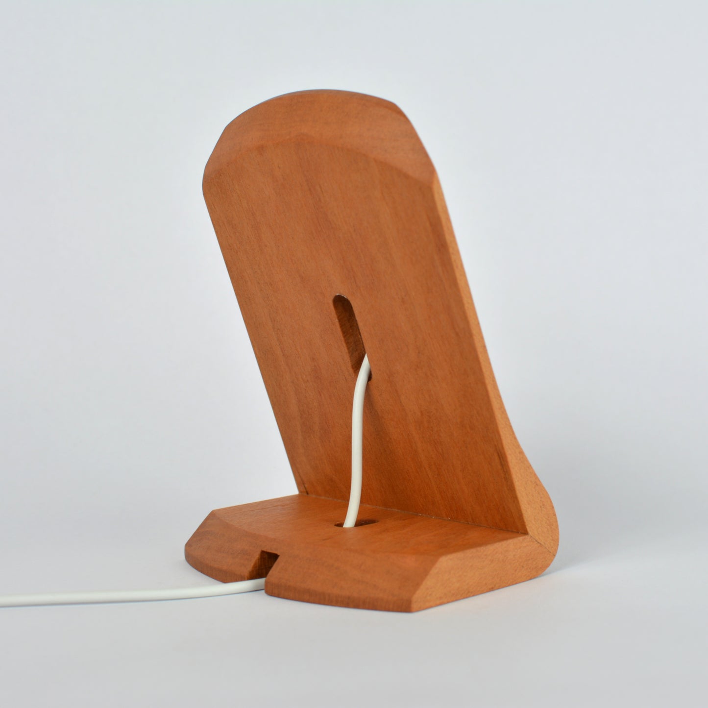 Wooden phone stand with a white cable on a light gray background