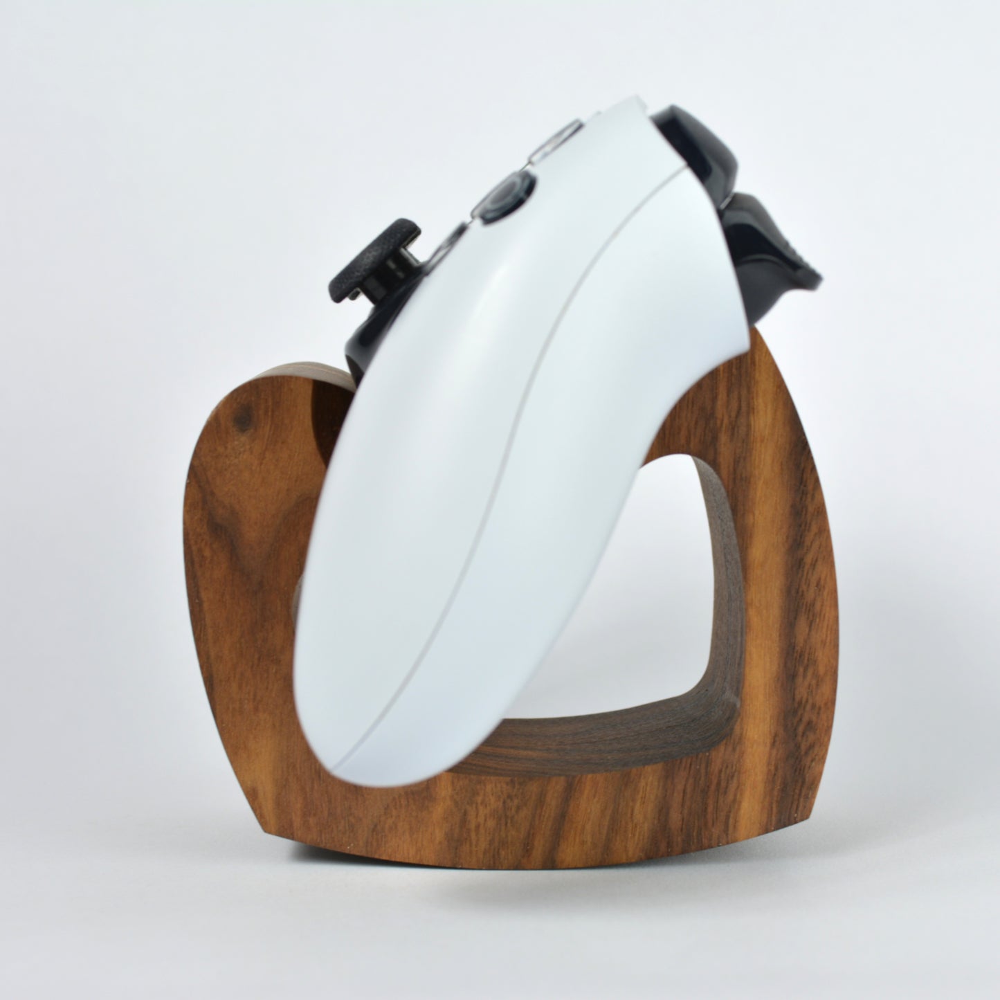 White gaming controller on a wooden stand against a white background