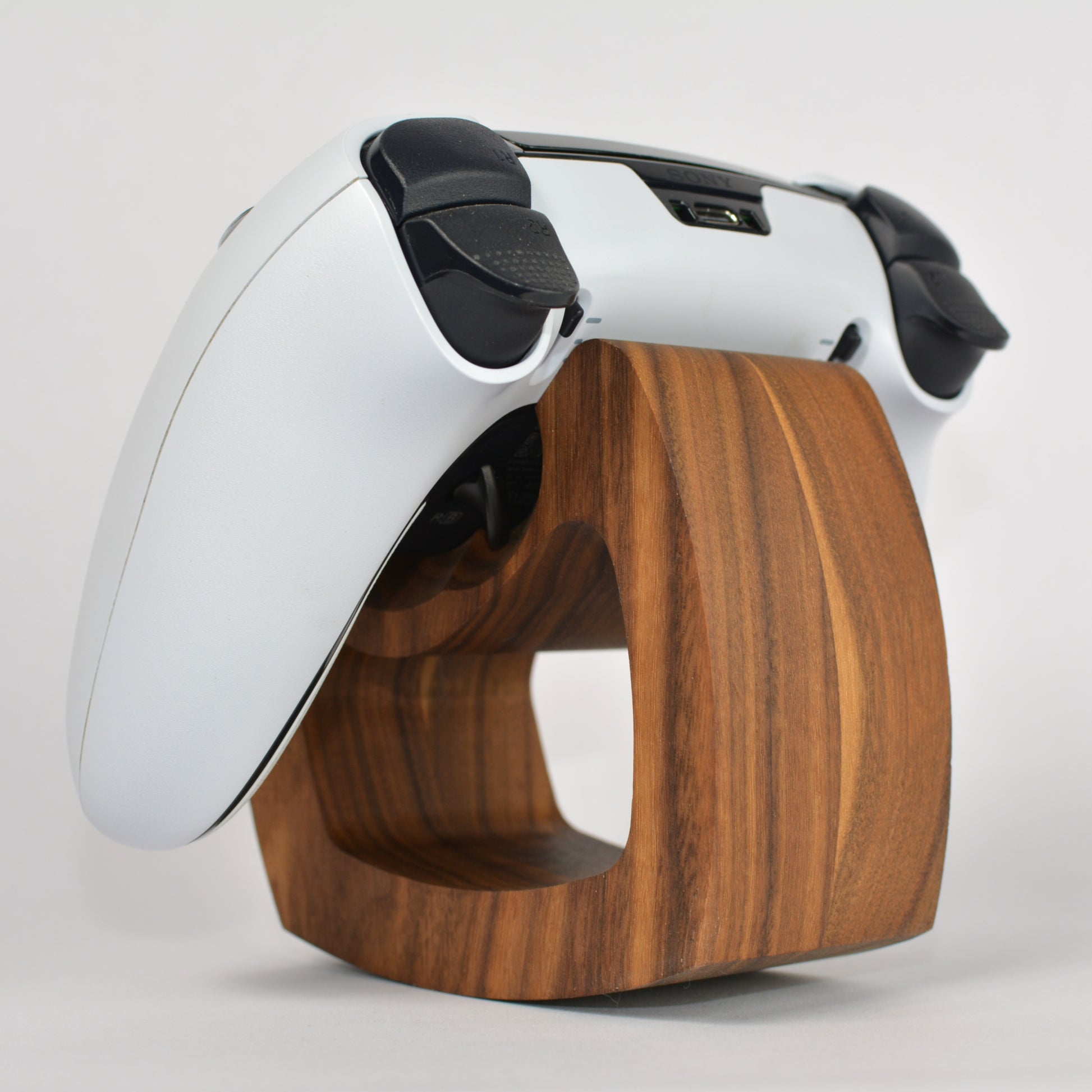 White gaming controller with black accents on a wooden stand against a white background