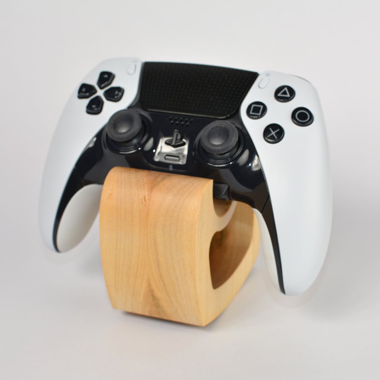 Black and white gaming controller on a wooden stand against a light gray background
