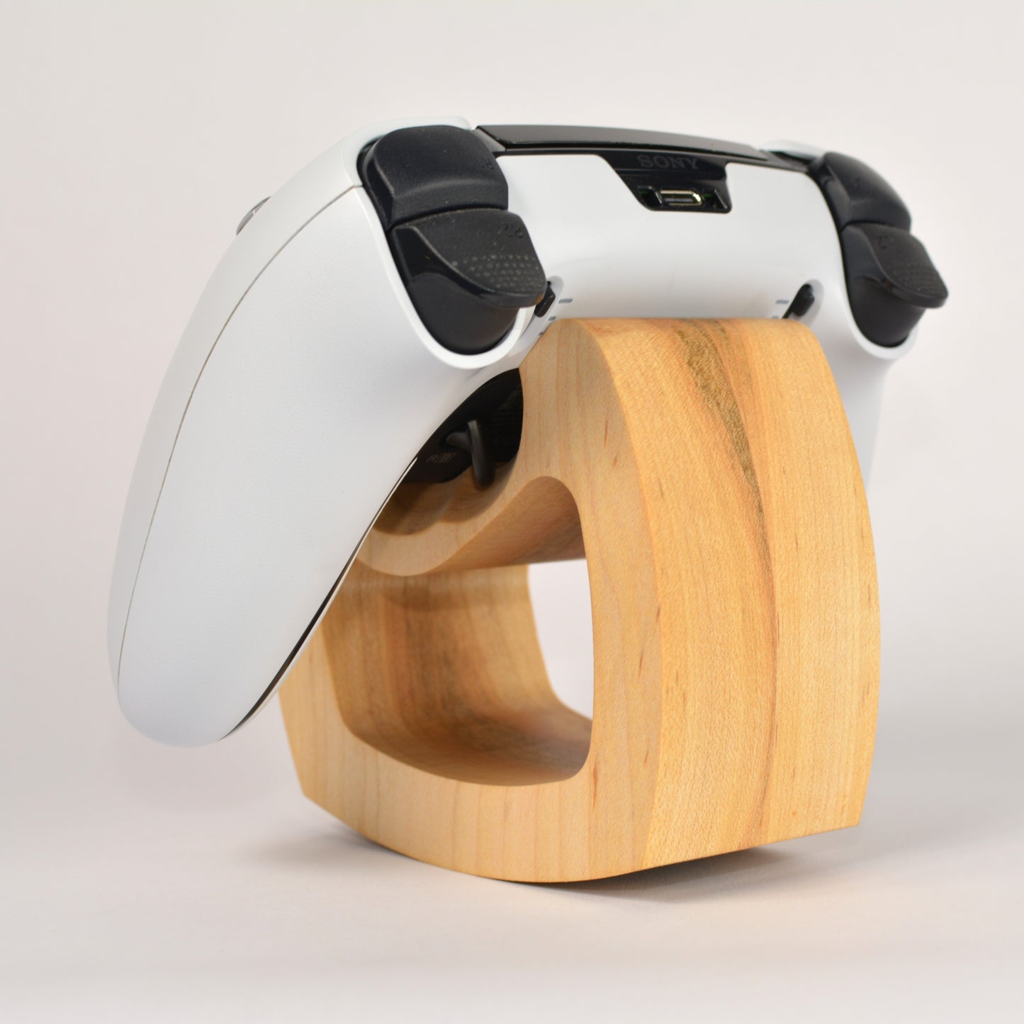 White and black electronic device on a wooden stand against a light background