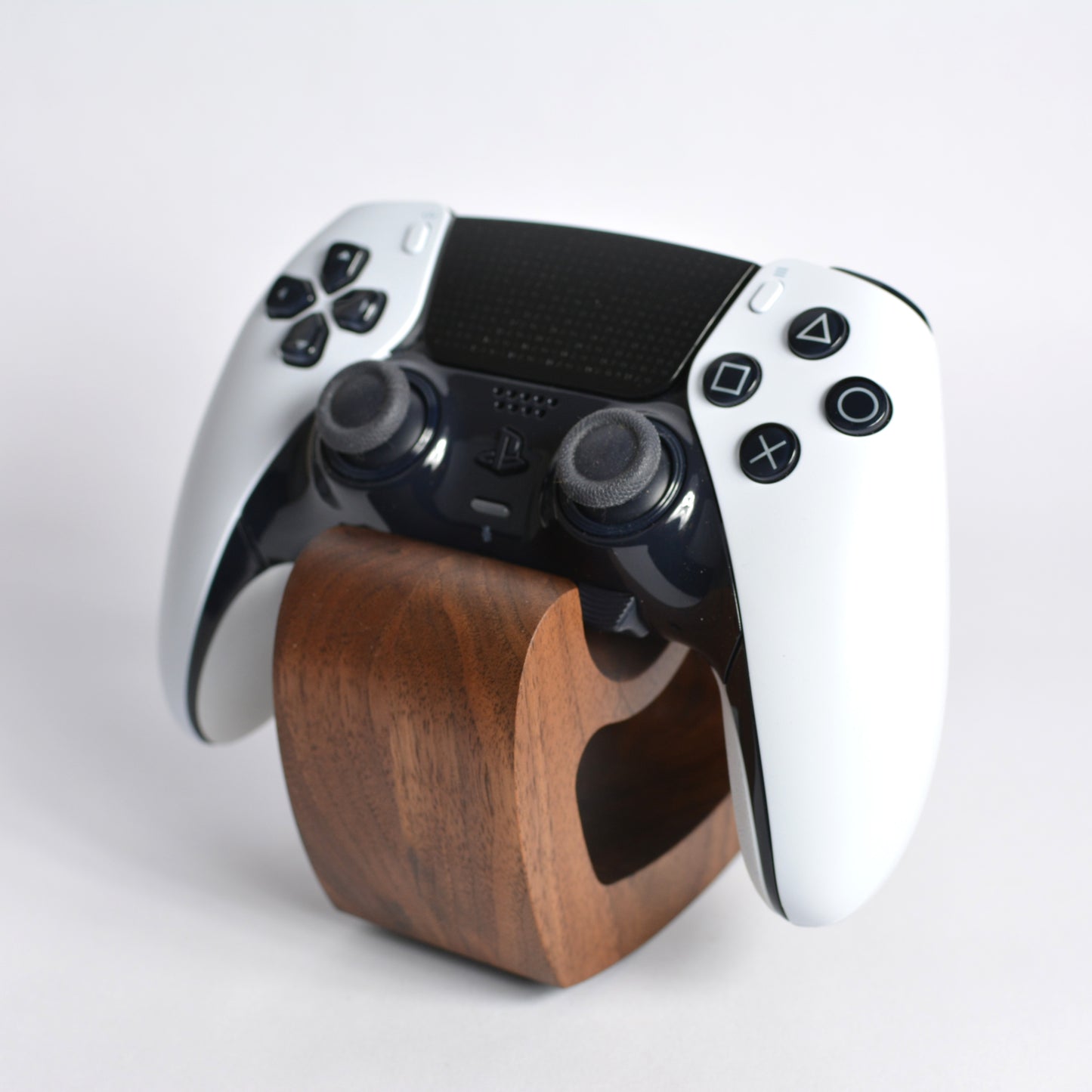 White gaming controller on a wooden stand against a light gray background