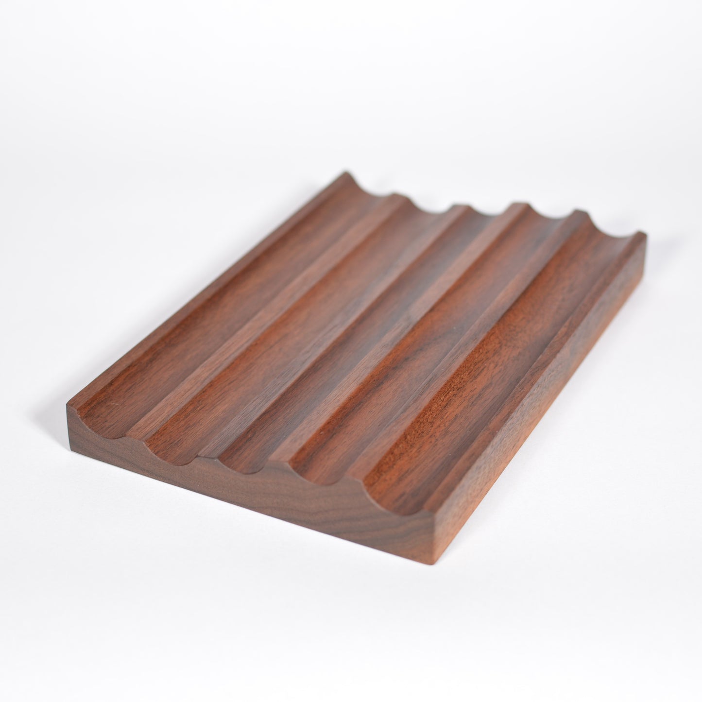A rectangular wooden fountain pen tray with five parallel raised ridges and a wavy edge, shown on a clean white background.
