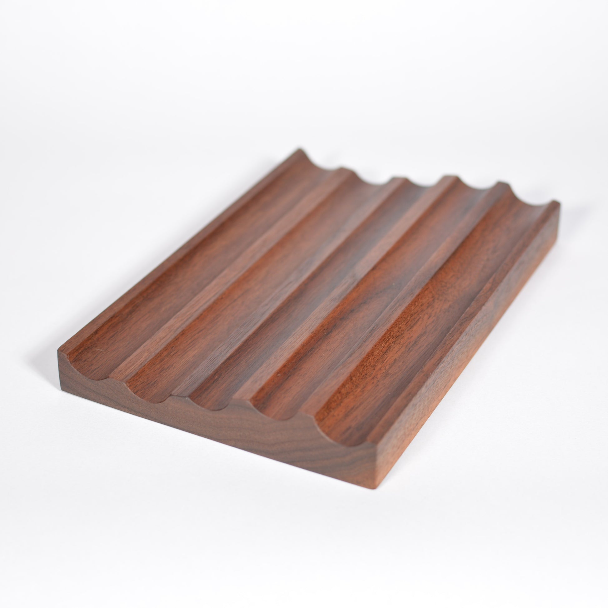 A rectangular wooden fountain pen tray with five parallel raised ridges and a wavy edge, shown on a clean white background.